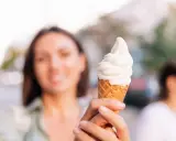 Kobieta trzyma lody na ból gardła. Słodka ochłoda w upalny dzień.