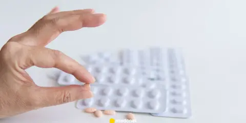 Szukasz co zamiast statyn na cholesterol? Dłoń trzyma tabletkę, w tle blistry leków.