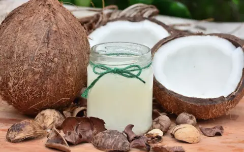 Cały kokos, jego połówki i słoiczek z olejem kokosowym. Czy kokos jest zdrowy? Tak, to naturalny produkt.