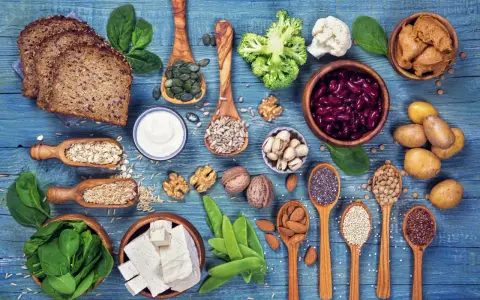 Różnorodne produkty bogate w białko dla wegetarian: tofu, soczewica, fasola, orzechy, nasiona, płatki owsiane, ryż, chleb pełnoziarnisty, jogurt, szpinak, brokuły, kalafior.